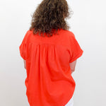 Person wearing an orange blouse with a plain white background
