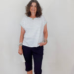 Woman wearing a striped shirt and dark pants against a plain background