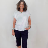 Woman wearing a striped shirt and dark pants against a plain background
