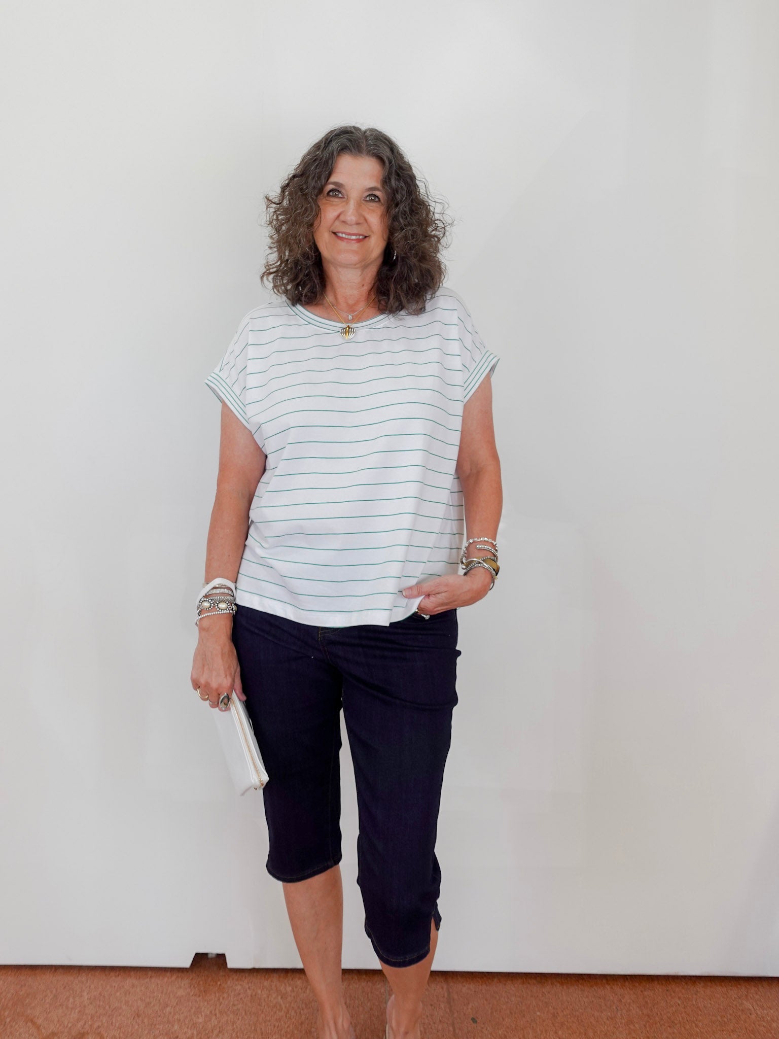 Woman wearing a striped shirt and dark pants against a plain background