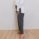 woman wearing a grey capri pant in front of a white wall. 