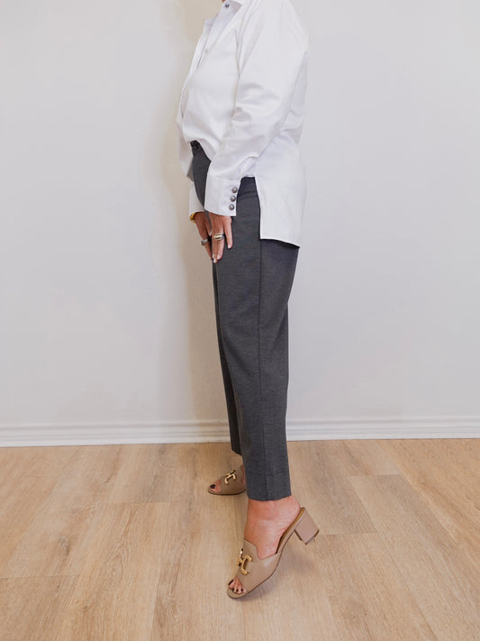 woman wearing a grey capri pant in front of a white wall. 