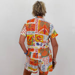 Person wearing a colorful patterned shirt and shorts set on a plain background