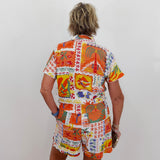 Person wearing a colorful patterned shirt and shorts set on a plain background