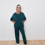 Person wearing a teal outfit with white sneakers against a plain background