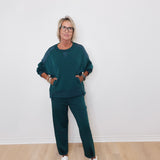 Person wearing a teal outfit with white sneakers against a plain background