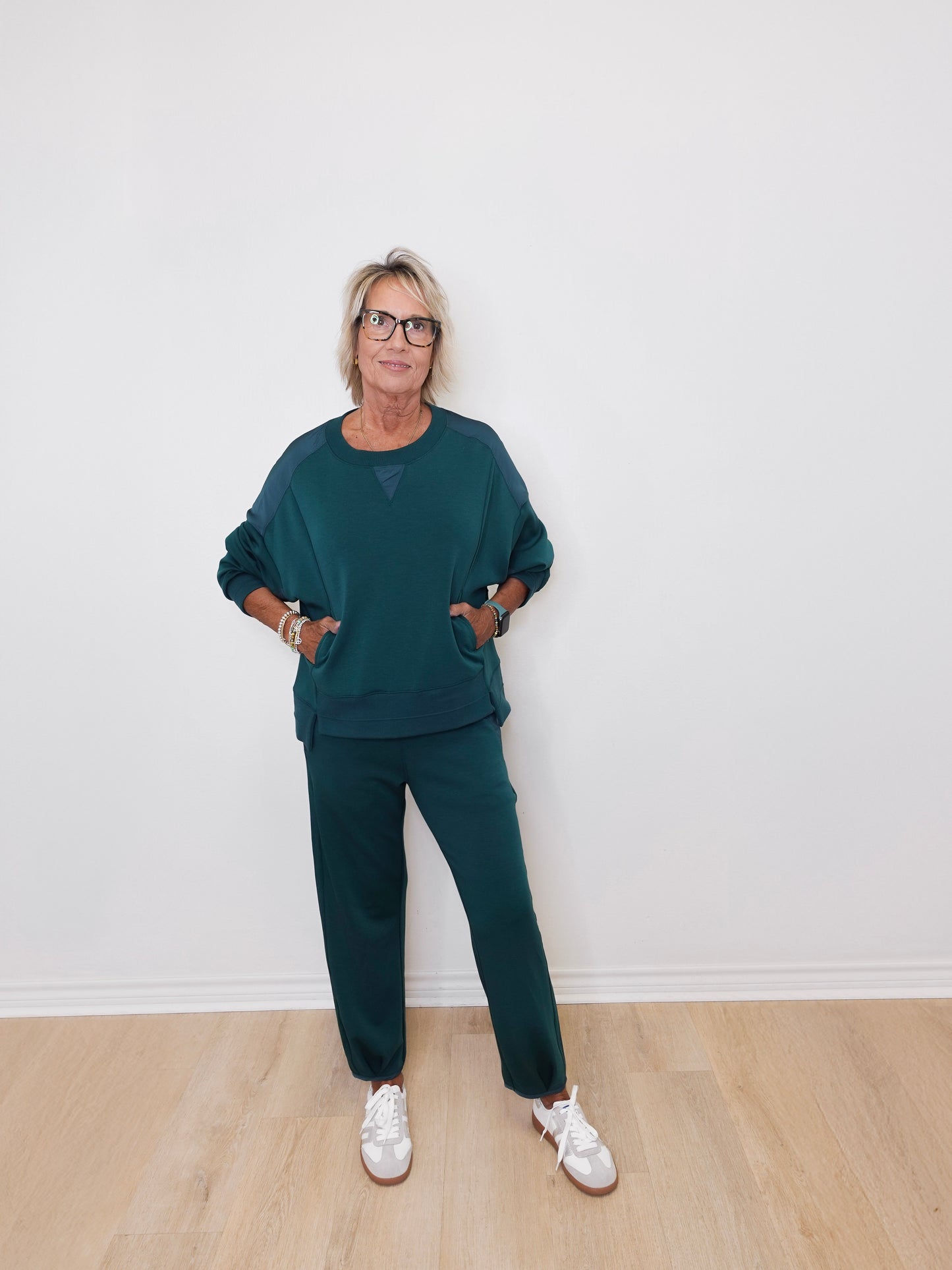 Person wearing a teal outfit with white sneakers against a plain background