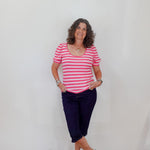 Woman wearing a pink and white striped shirt with navy pants against a plain background