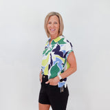 Woman wearing a colorful patterned shirt and black shorts against a white background