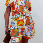 Person wearing a colorful patterned outfit with a belt against a white background