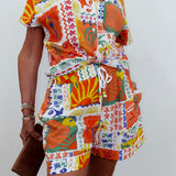 Person wearing a colorful patterned outfit with a belt against a white background