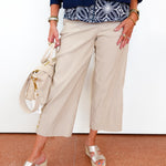 Person wearing a blue jacket, patterned top, beige wide-leg pants, and silver sandals on a white background.