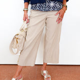 Person wearing a blue jacket, patterned top, beige wide-leg pants, and silver sandals on a white background.
