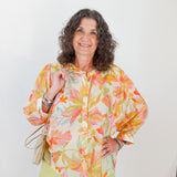 Woman wearing a colorful floral blouse against a white background