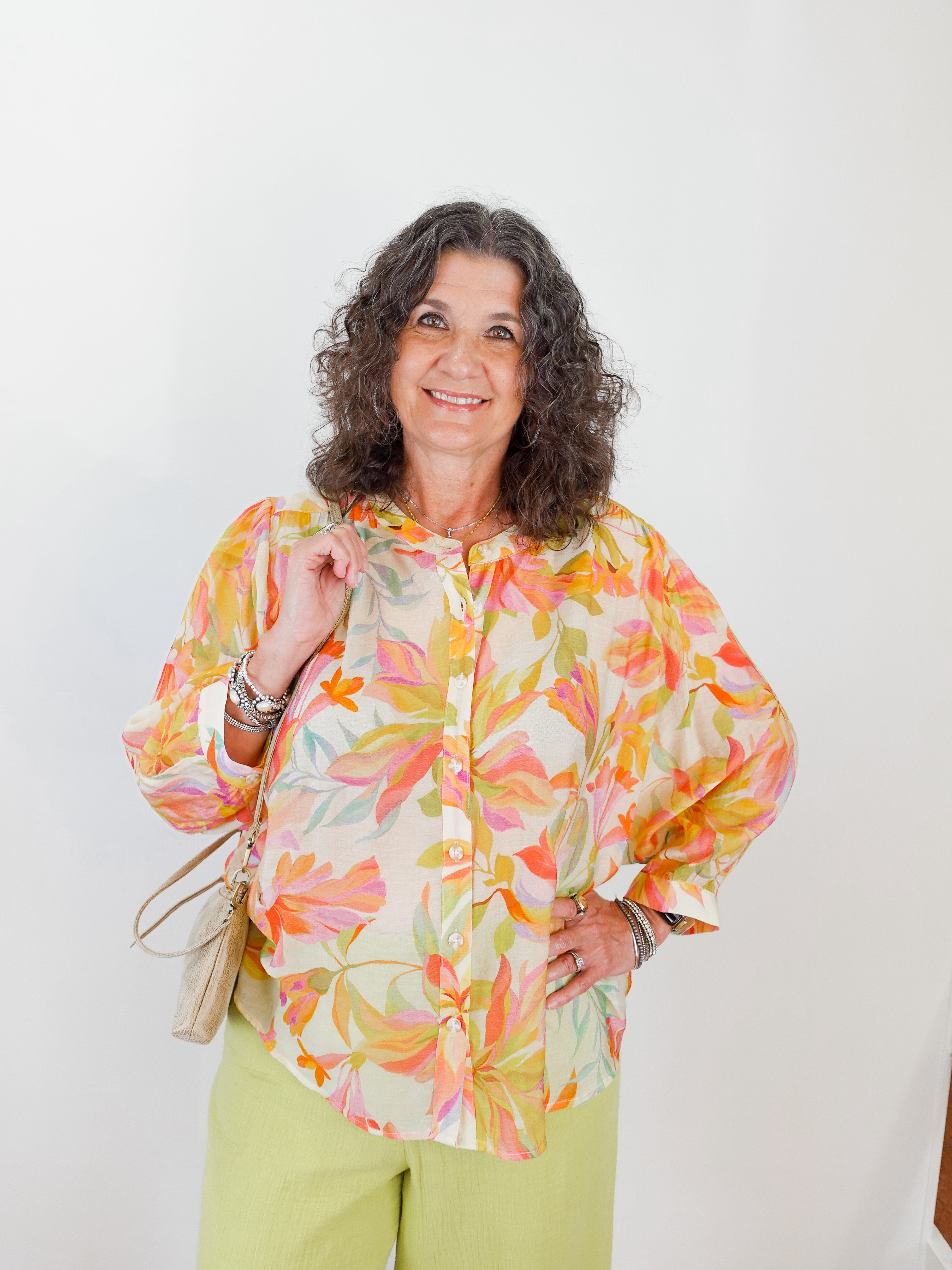 Woman wearing a colorful floral blouse against a white background