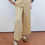 Person wearing beige wide-leg pants and brown shoes on a plain background