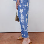 Person wearing blue floral pants with a plain background