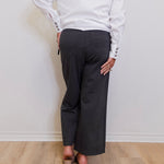 woman wearing a grey capri pant in front of a white wall. 