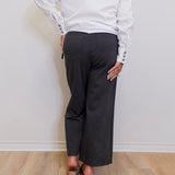 woman wearing a grey capri pant in front of a white wall. 