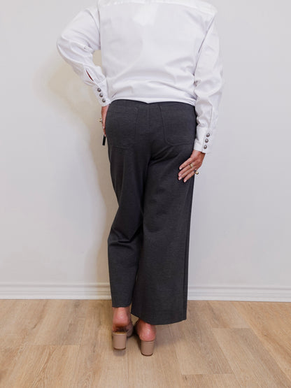 woman wearing a grey capri pant in front of a white wall. 
