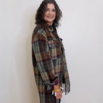 Woman wearing a plaid shawl against a white wall