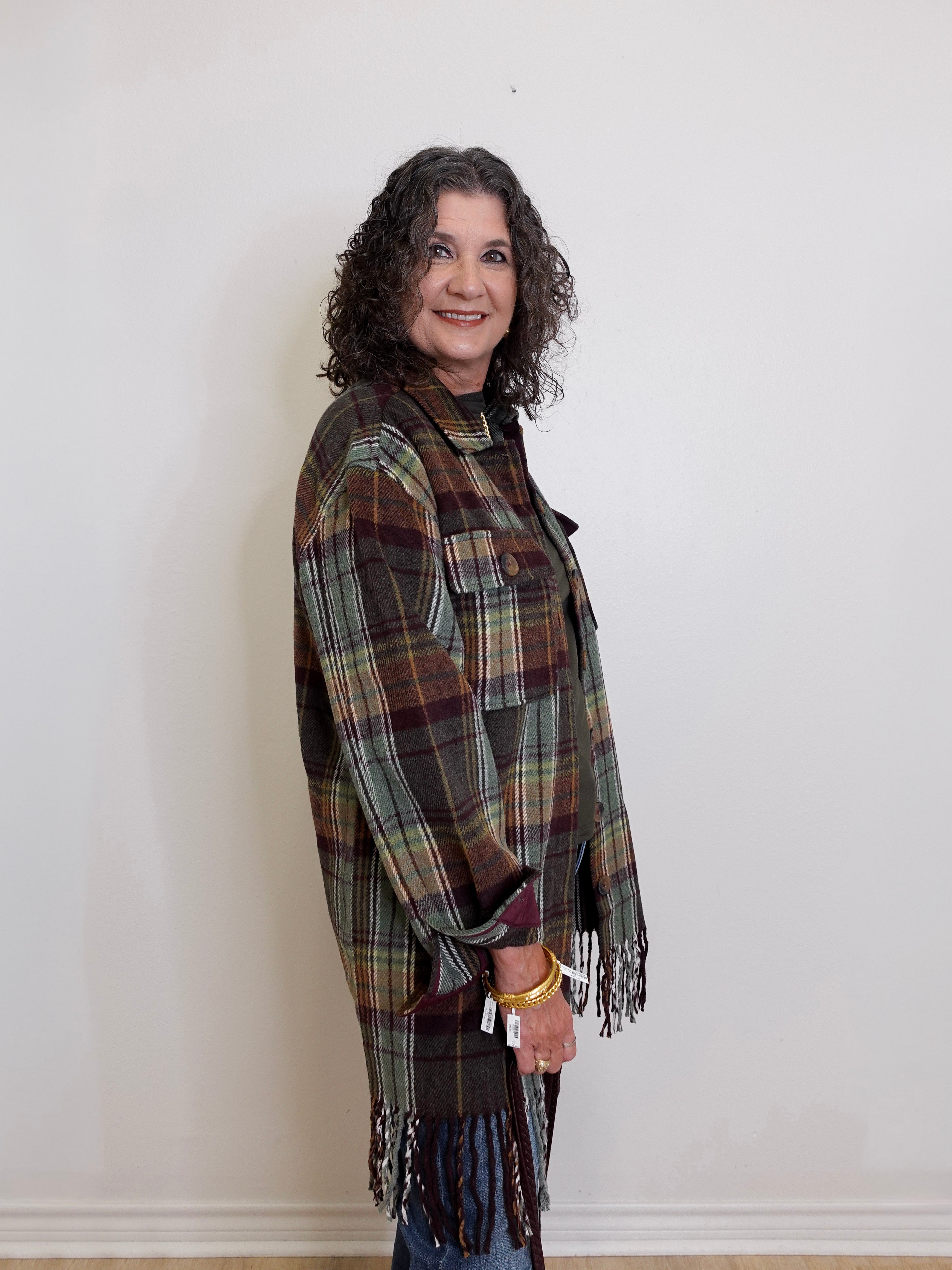 Woman wearing a plaid shawl against a white wall