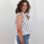 Woman wearing a striped sleeveless top and blue jeans against a white background