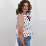 Woman wearing a striped sleeveless top and blue jeans against a white background