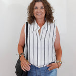 Woman wearing a striped sleeveless shirt and jeans against a white background