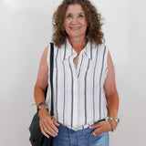 Woman wearing a striped sleeveless shirt and jeans against a white background