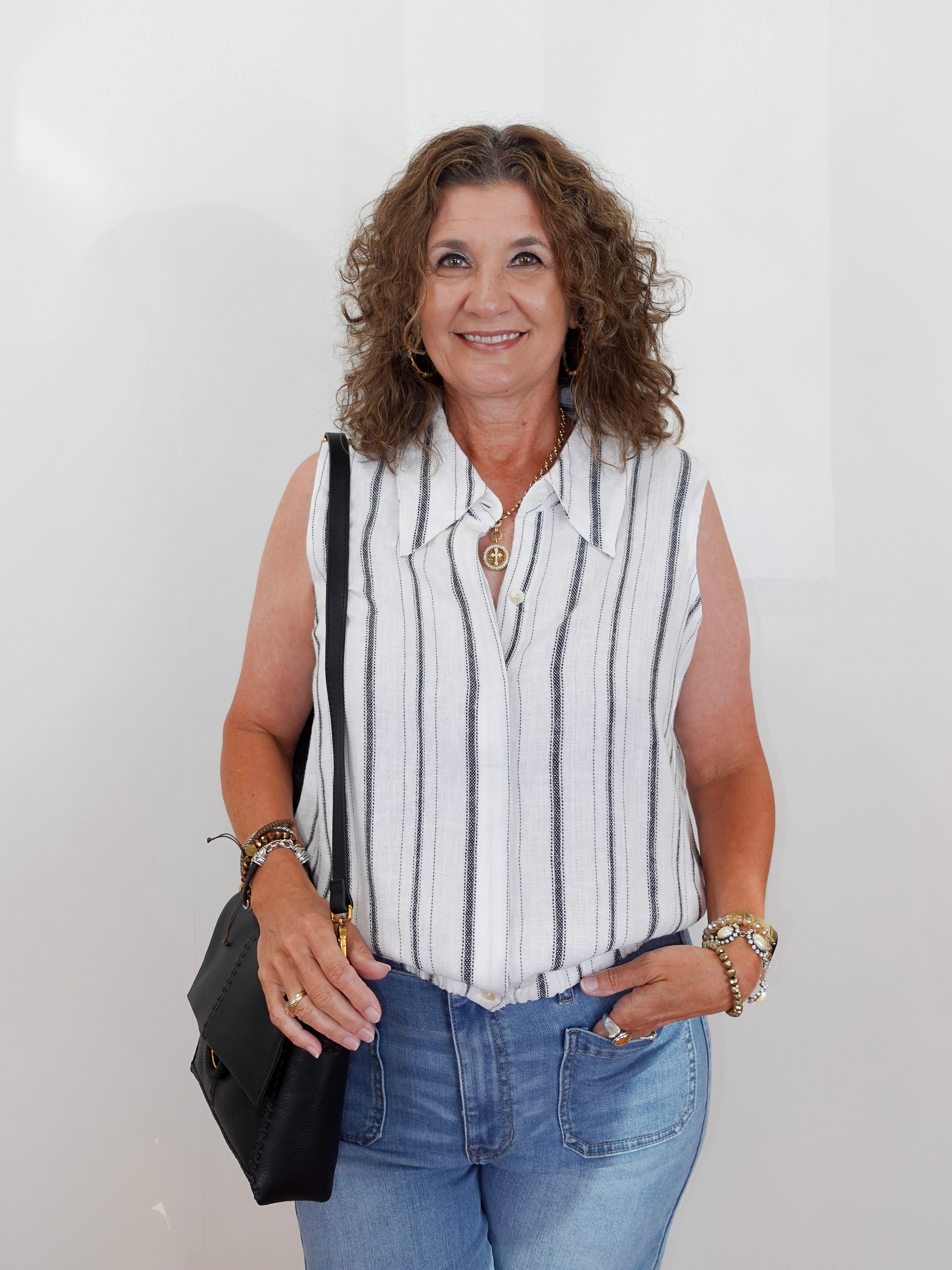 Woman wearing a striped sleeveless shirt and jeans against a white background