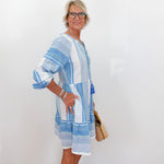Woman wearing a blue and white striped dress against a white background