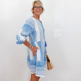 Woman wearing a blue and white striped dress against a white background