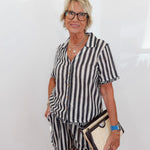 Woman wearing a black and white striped dress with a plain background
