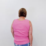 Person wearing a pink tank top and blue floral pants against a white background