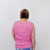 Person wearing a pink tank top and blue floral pants against a white background