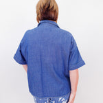 Person wearing a blue shirt and floral pants against a white background