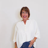 Woman wearing a white blouse and blue jeans against a plain background