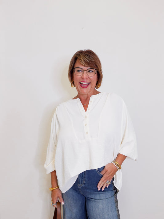 Woman wearing a white blouse and blue jeans against a plain background