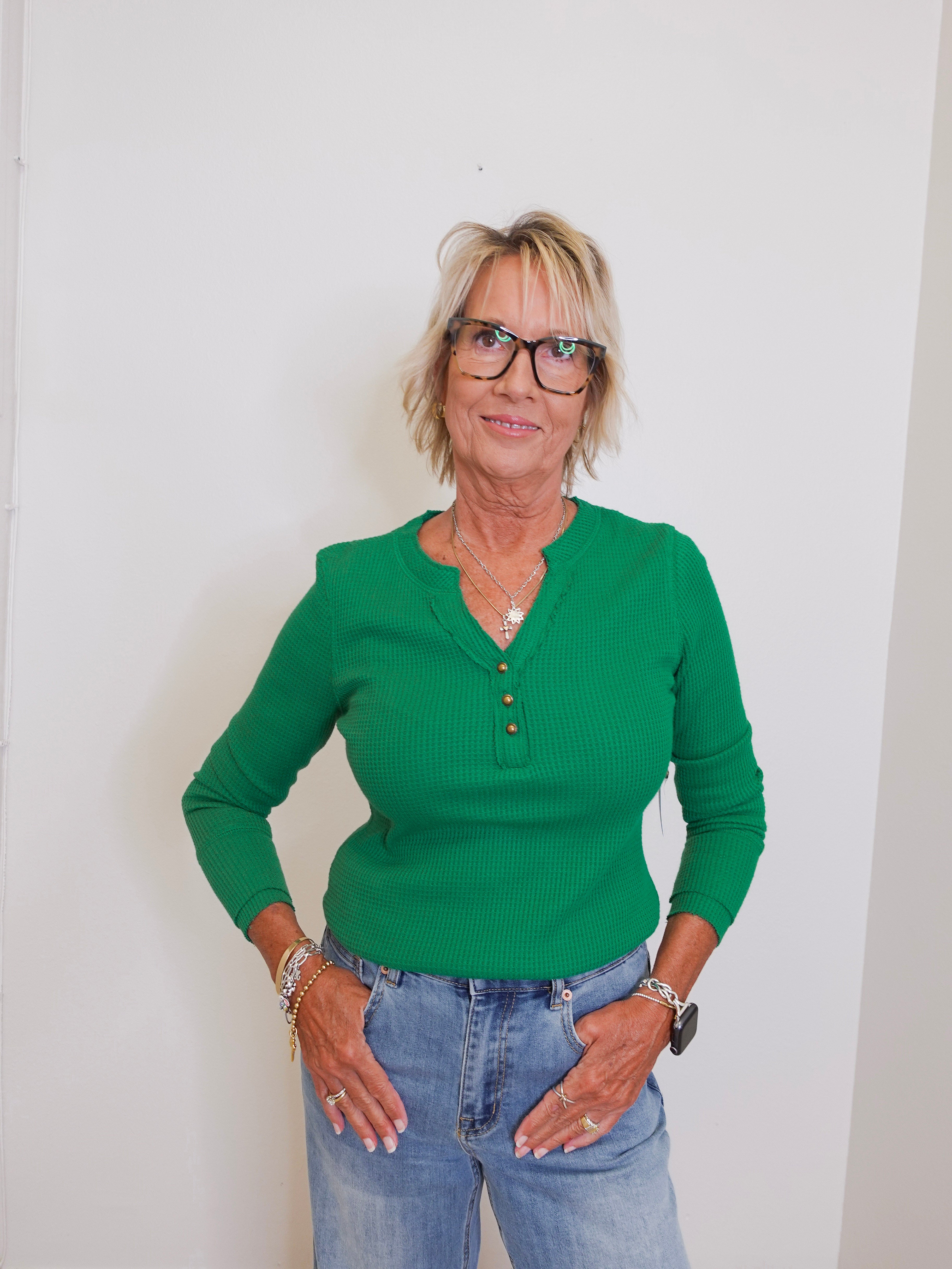 Woman wearing a green sweater and blue jeans against a white background