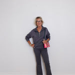Woman in gray outfit standing against a white wall