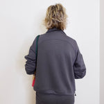 Person wearing a gray tracksuit against a white wall
