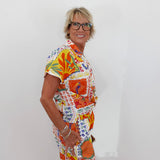 Woman wearing a colorful patterned outfit against a white background