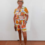 Woman wearing a colorful patterned outfit against a white wall.