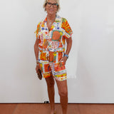 Woman wearing a colorful patterned outfit against a white wall.