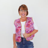 Woman wearing a colorful quilted vest over a white shirt with blue jeans on a white background