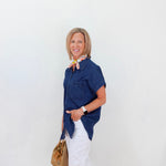 Woman wearing a blue shirt and white pants against a white background