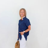Woman wearing a blue shirt and white pants against a white background