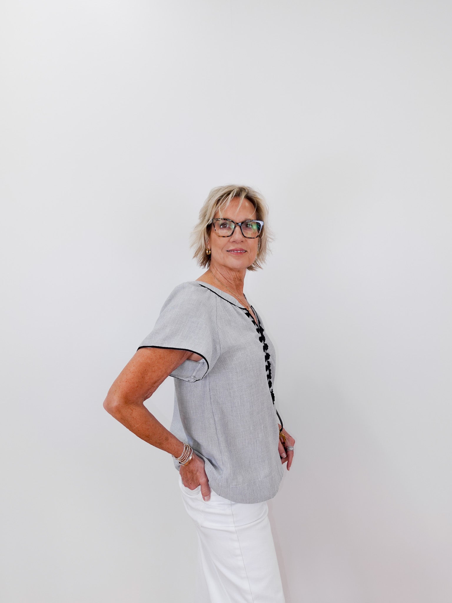 Woman wearing a gray short-sleeve shirt with a black trim against a white background