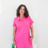 Woman wearing a pink dress holding a green bag against a white background